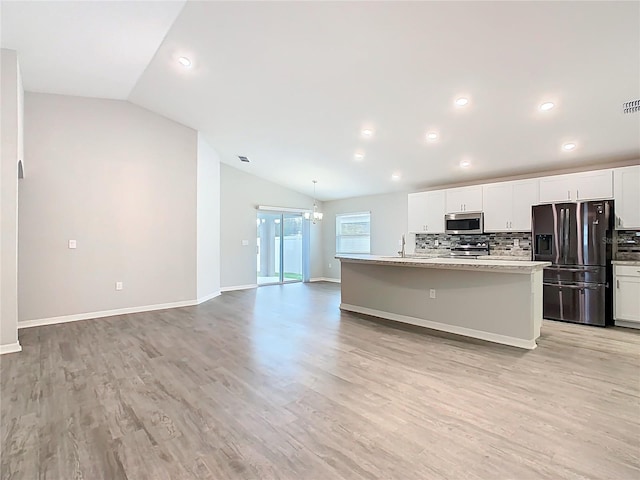 kitchen with a sink, vaulted ceiling, white cabinetry, and stainless steel appliances