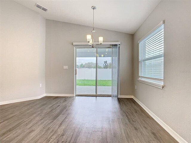 spare room featuring a wealth of natural light, visible vents, lofted ceiling, and dark wood-style flooring