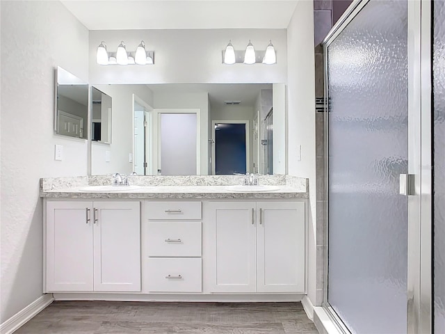 bathroom with a shower stall, wood finished floors, and a sink