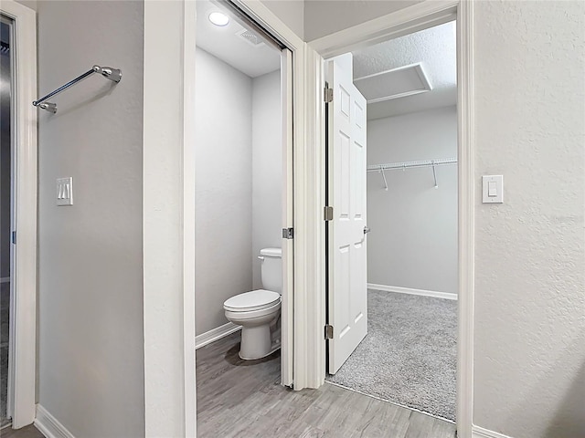 bathroom featuring toilet, wood finished floors, visible vents, and baseboards