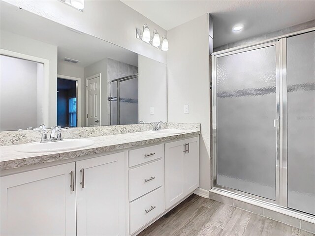 bathroom featuring a sink, visible vents, wood finished floors, and a shower stall