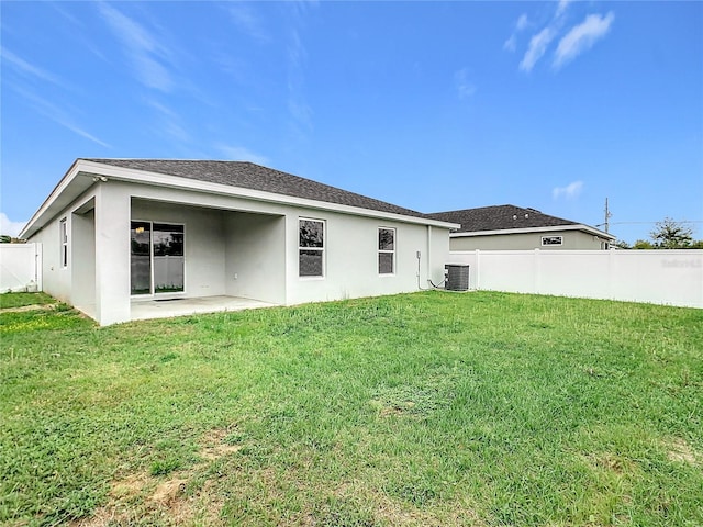 rear view of property with central air condition unit, stucco siding, a yard, and fence