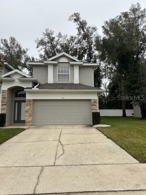 traditional-style home with an attached garage, stone siding, concrete driveway, and a front yard