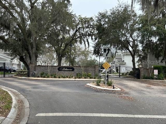 view of street with a gate, traffic signs, a gated entry, and curbs