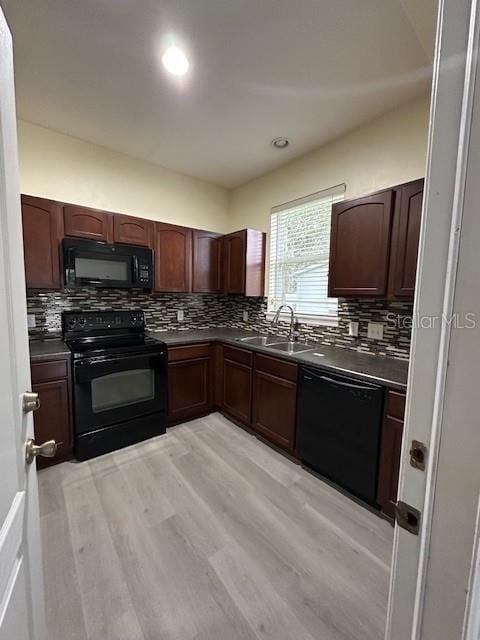 kitchen featuring black appliances, dark countertops, a sink, and decorative backsplash