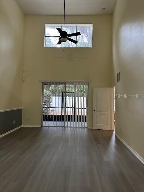 unfurnished living room with wood finished floors, visible vents, and baseboards