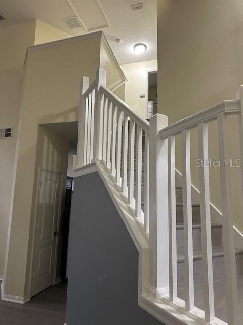 stairway featuring wood finished floors and visible vents