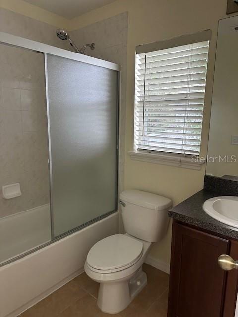 bathroom with tile patterned flooring, combined bath / shower with glass door, vanity, and toilet