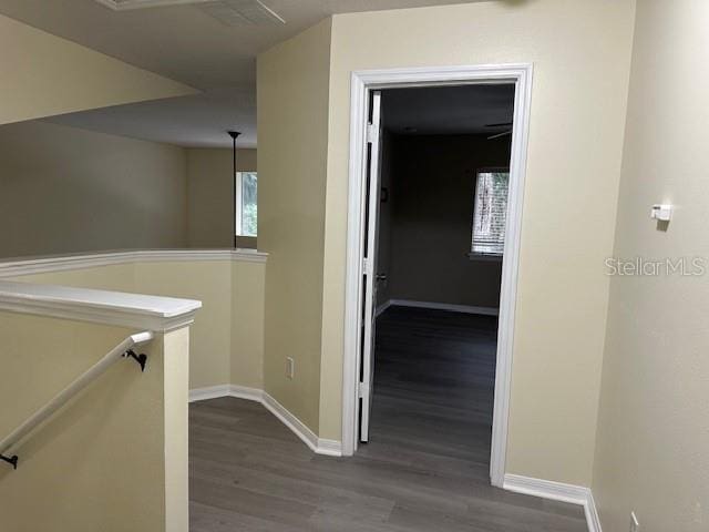 corridor featuring dark wood-type flooring, baseboards, and an upstairs landing