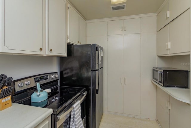 kitchen featuring visible vents, stainless steel electric range, freestanding refrigerator, light countertops, and white cabinetry