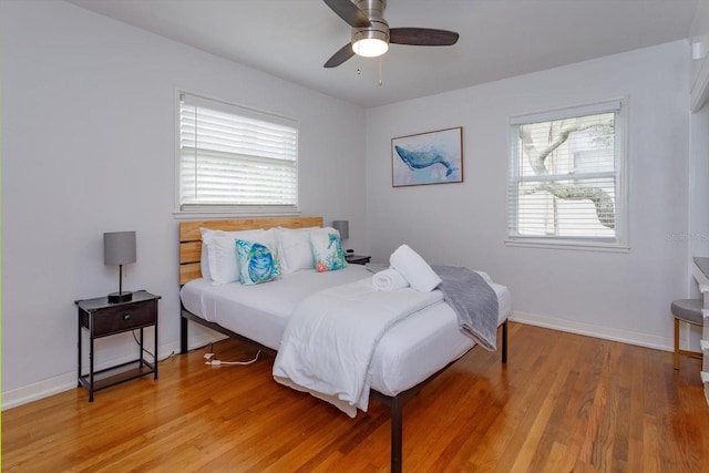 bedroom featuring baseboards, multiple windows, light wood-style flooring, and a ceiling fan