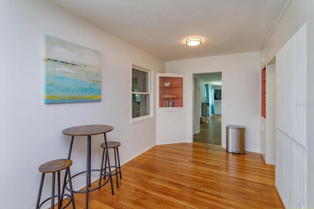 hall with baseboards and light wood finished floors