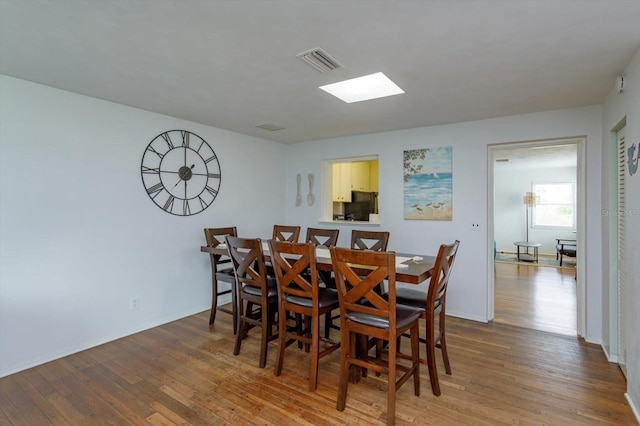 dining area with visible vents, light wood-type flooring, and baseboards