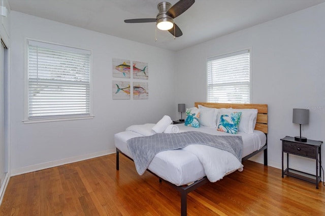 bedroom with a ceiling fan, light wood-style floors, and baseboards