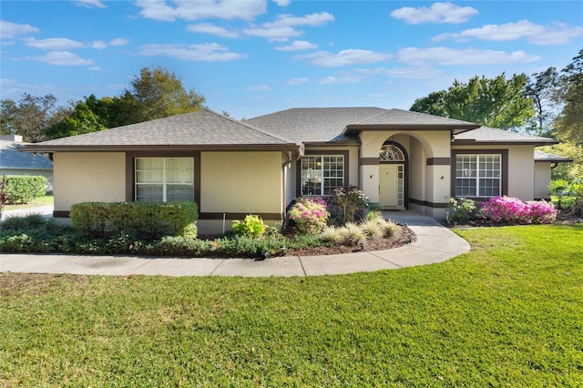 single story home featuring a front yard, roof with shingles, and stucco siding