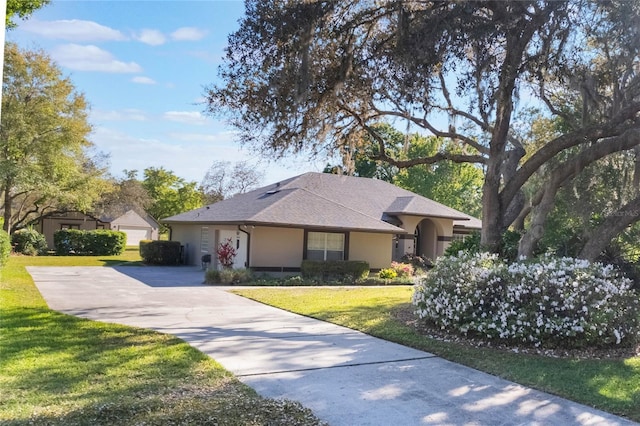 single story home featuring roof with shingles, an attached garage, stucco siding, a front lawn, and concrete driveway