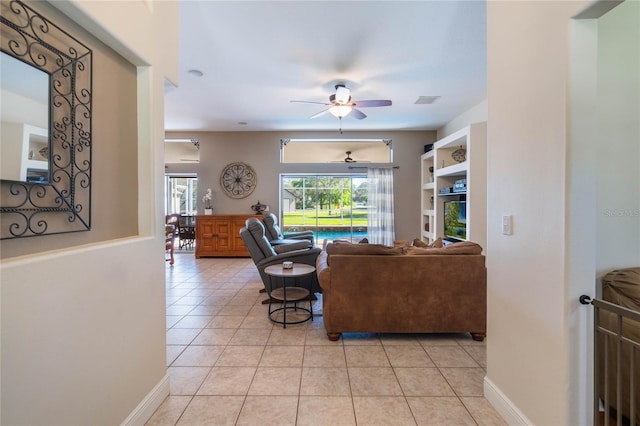 living room with light tile patterned floors, visible vents, baseboards, and a ceiling fan