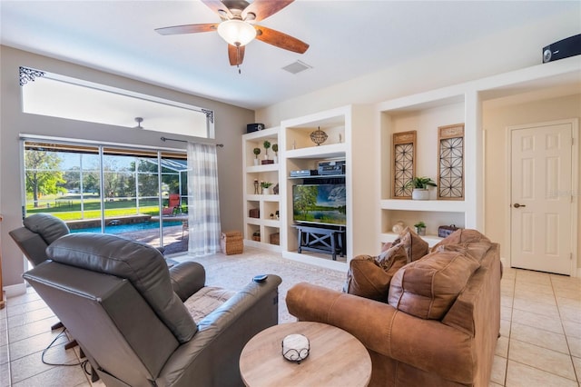 living area with light tile patterned floors, visible vents, built in shelves, and a ceiling fan