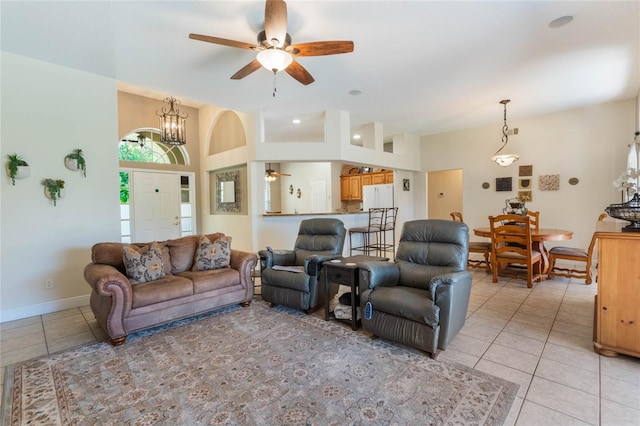 living area featuring baseboards, light tile patterned flooring, and ceiling fan with notable chandelier