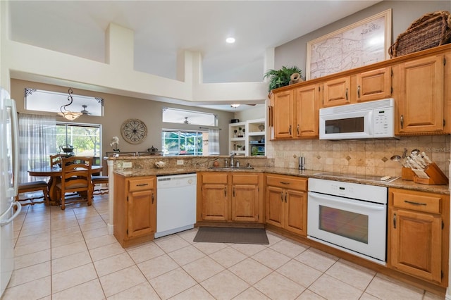 kitchen with white appliances, a peninsula, backsplash, and a sink