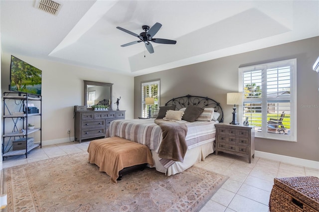 bedroom featuring light tile patterned floors, visible vents, baseboards, and a tray ceiling