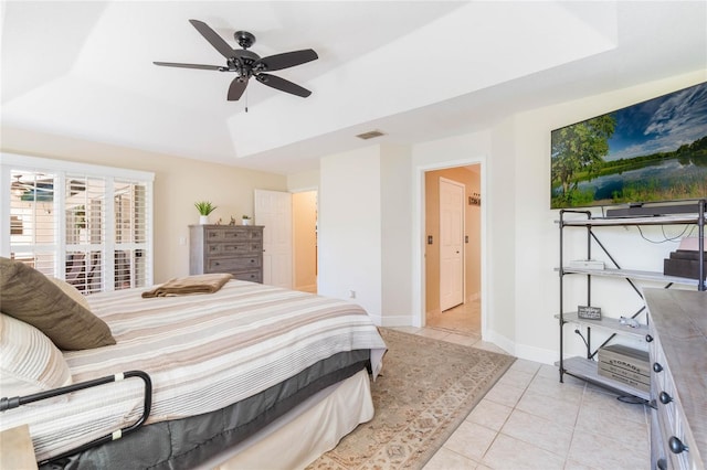 bedroom featuring light tile patterned floors, visible vents, baseboards, ceiling fan, and a raised ceiling