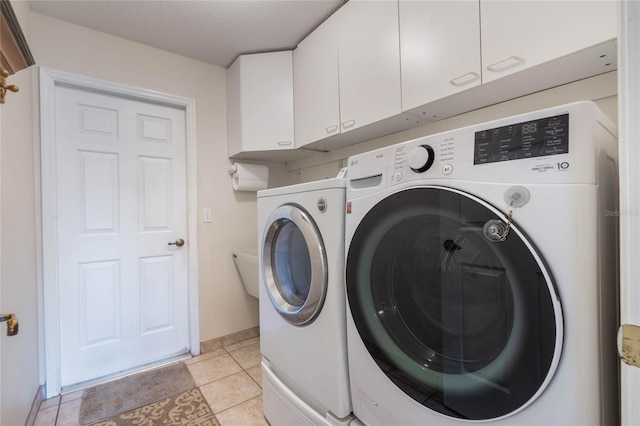 washroom with baseboards, light tile patterned floors, cabinet space, a textured ceiling, and separate washer and dryer