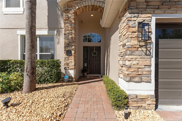 view of exterior entry with stone siding and stucco siding