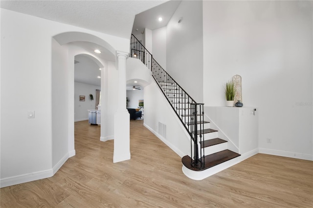 staircase with visible vents, baseboards, recessed lighting, wood finished floors, and arched walkways