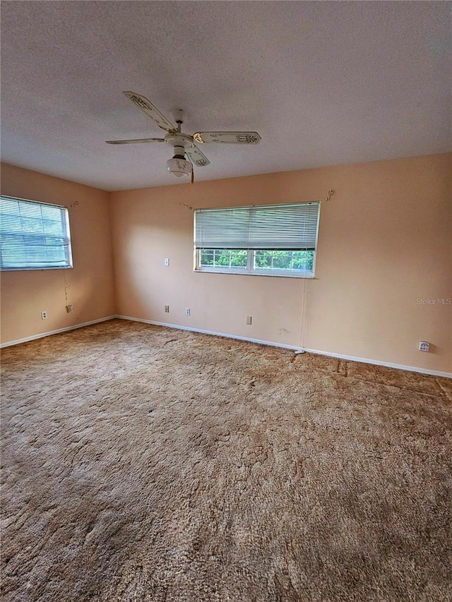 carpeted empty room with a ceiling fan, baseboards, and a textured ceiling