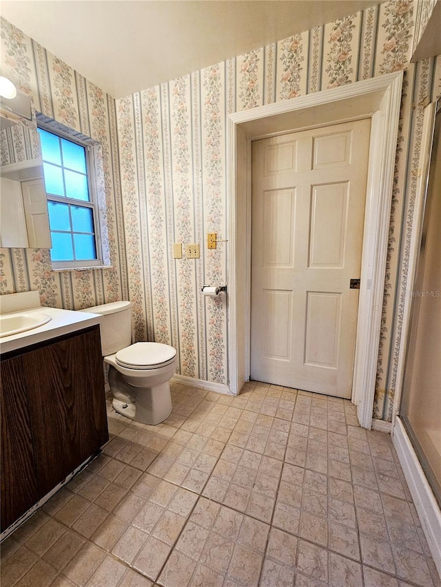 full bath with a shower stall, wallpapered walls, toilet, brick patterned floor, and vanity