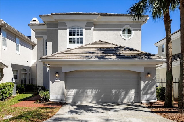 view of front of property featuring a garage, fence, a tile roof, and stucco siding