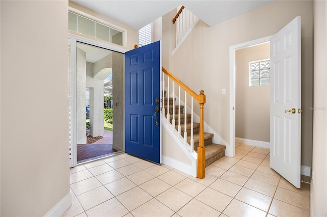 entrance foyer featuring stairs, baseboards, and light tile patterned floors