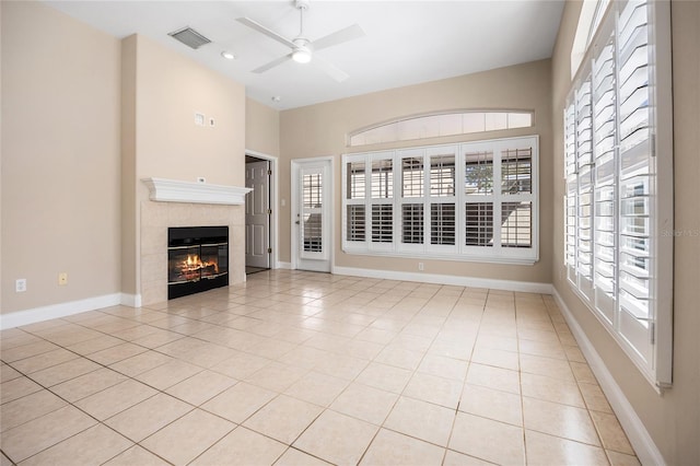 unfurnished living room featuring light tile patterned floors, ceiling fan, a tile fireplace, visible vents, and baseboards