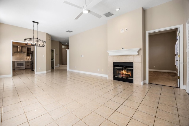 unfurnished living room featuring a tile fireplace, visible vents, ceiling fan, and light tile patterned floors