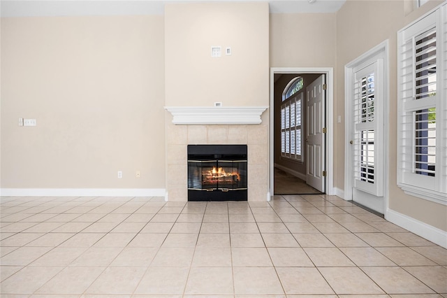 foyer entrance with a fireplace, baseboards, and light tile patterned flooring