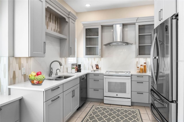 kitchen featuring light tile patterned floors, gray cabinetry, stainless steel appliances, a sink, and wall chimney range hood