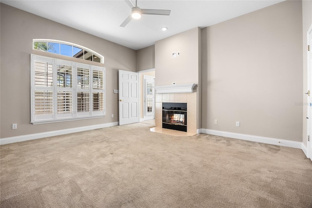 unfurnished living room featuring carpet floors, a fireplace, baseboards, and ceiling fan