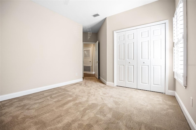 unfurnished bedroom featuring baseboards, carpet, visible vents, and a closet