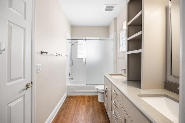 bathroom with double vanity, visible vents, toilet, wood finished floors, and a sink