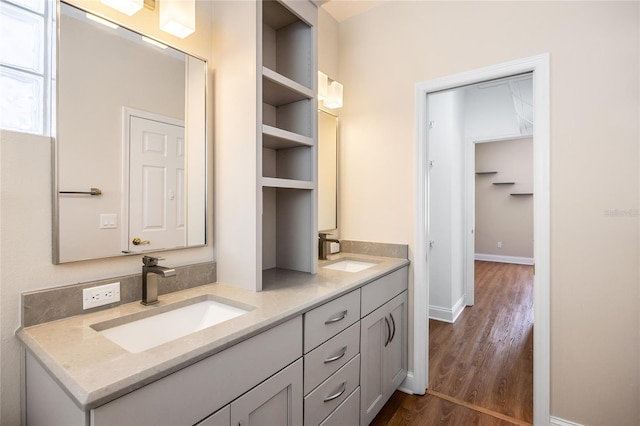 bathroom with double vanity, a sink, baseboards, and wood finished floors