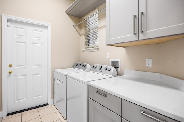 clothes washing area with light tile patterned floors, cabinet space, and washer and dryer