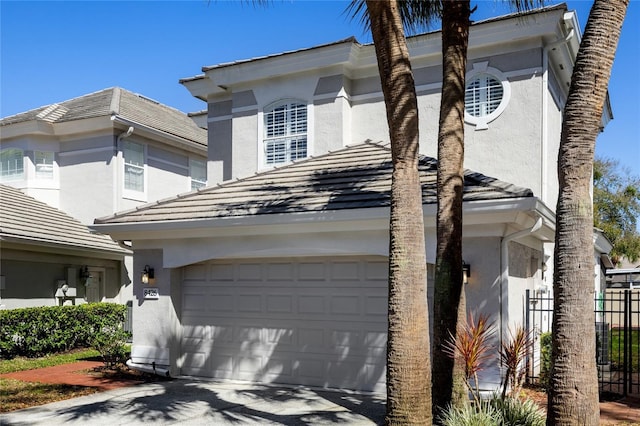 view of front facade featuring a tiled roof, driveway, and stucco siding