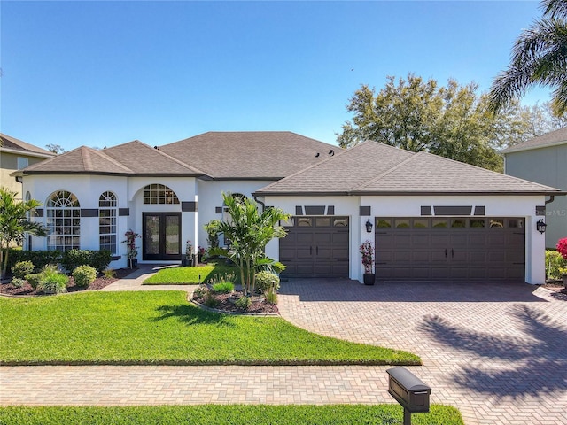 view of front of house featuring a garage, stucco siding, decorative driveway, and a front yard