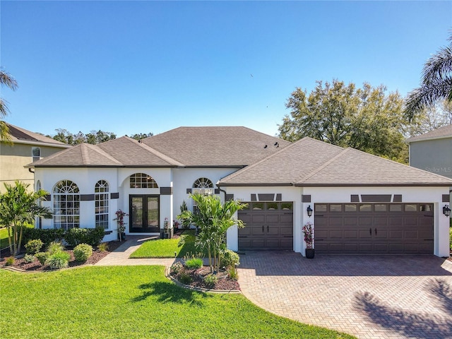 view of front of house with decorative driveway, french doors, a shingled roof, a garage, and a front lawn