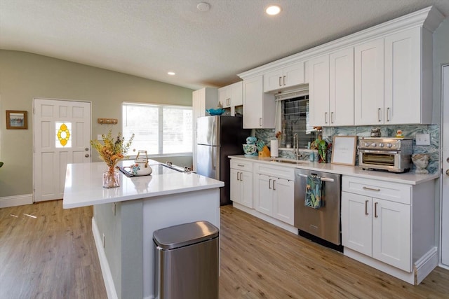 kitchen featuring white cabinetry, stainless steel appliances, lofted ceiling, and a sink