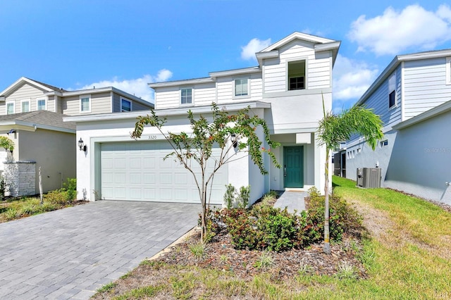 view of front of property featuring a garage, decorative driveway, stucco siding, and central AC unit