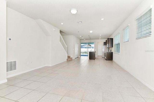 unfurnished living room featuring light tile patterned floors, recessed lighting, visible vents, baseboards, and stairs