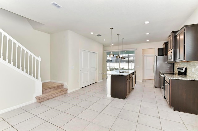 kitchen with tasteful backsplash, a center island with sink, visible vents, appliances with stainless steel finishes, and dark brown cabinets