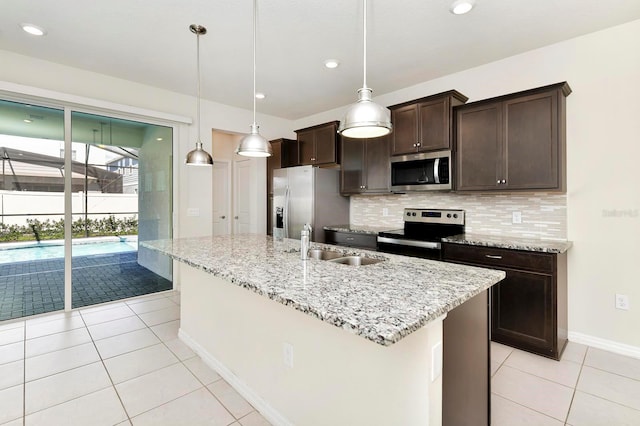 kitchen with dark brown cabinetry, light tile patterned floors, a center island with sink, decorative backsplash, and stainless steel appliances